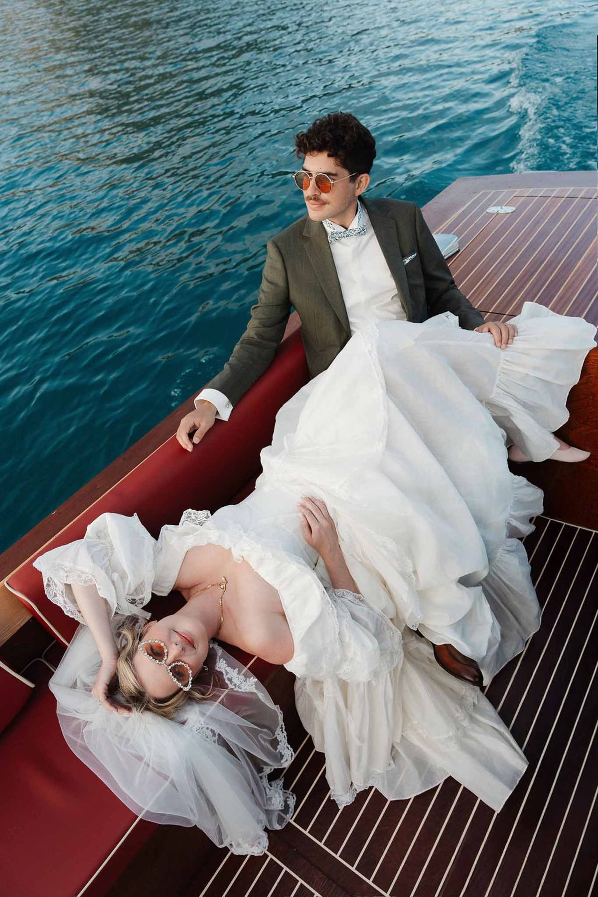 Couple lounging on wooden speedboat on turquoise Lake Annecy at Palace de Menthon