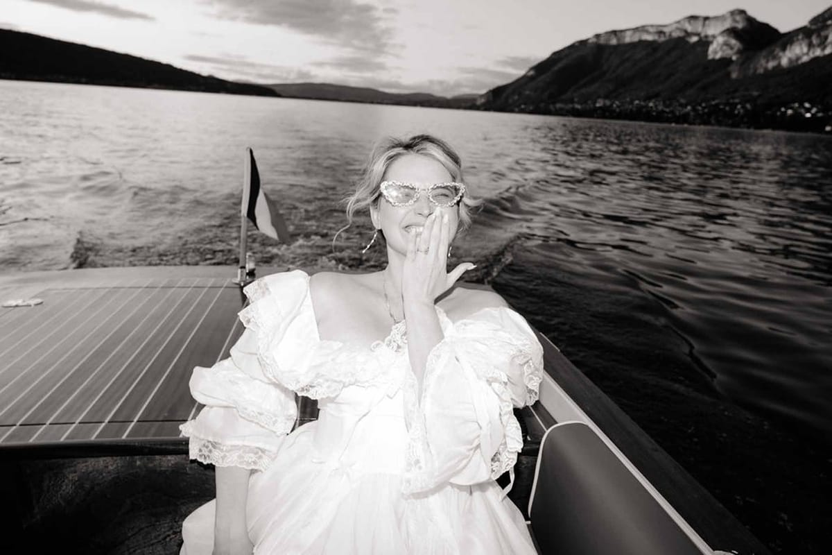 Bride blowing kiss on speedboat on Lake Annecy in black and white at Palace de Menthon