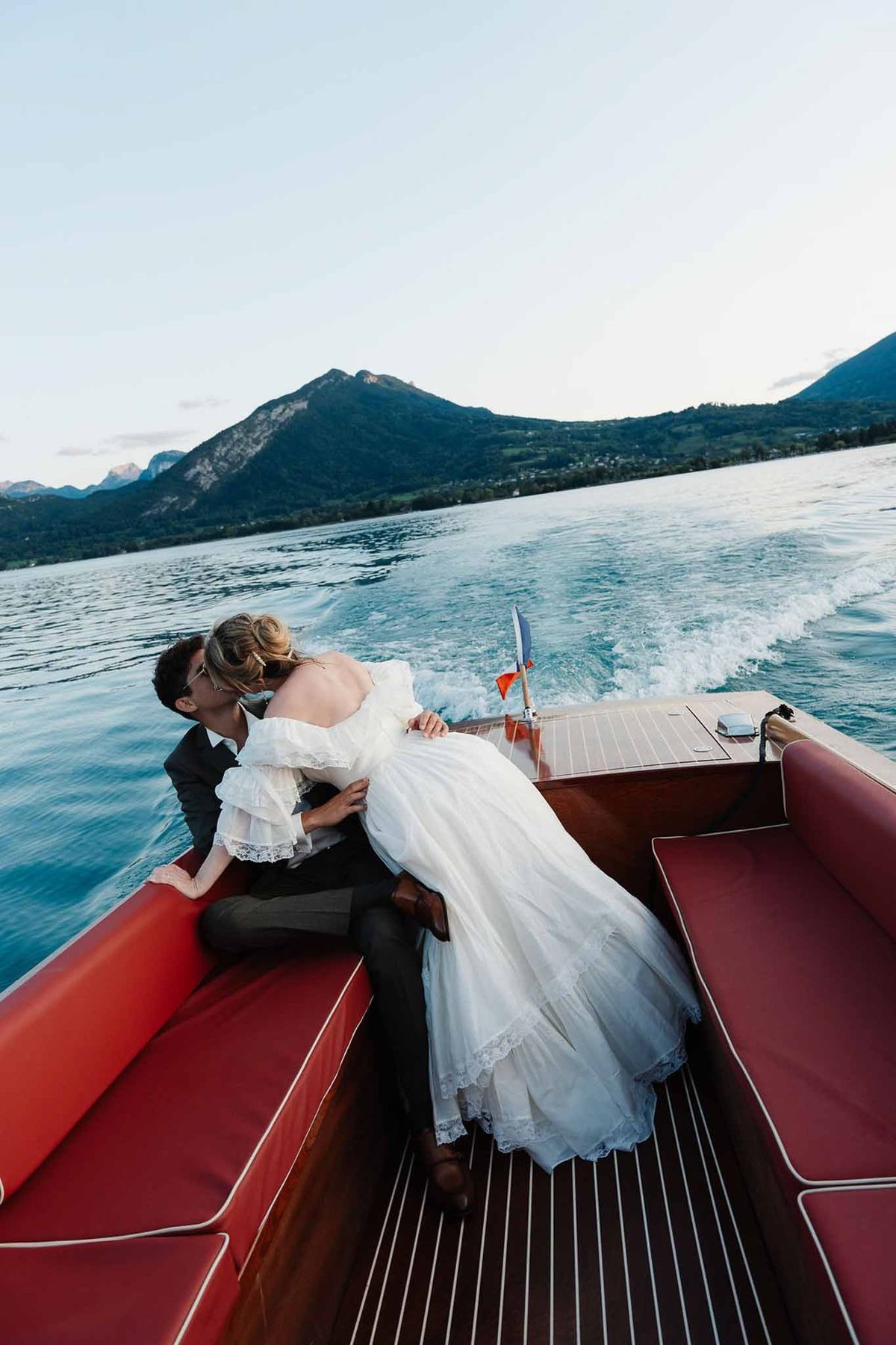Couple kissing on speedboat with Alpine mountains on Lake Annecy at Palace de Menthon