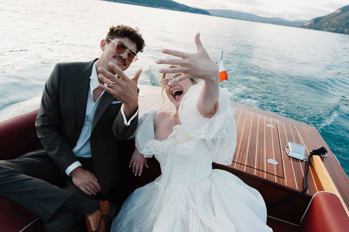 Couple showing wedding rings laughing on speedboat on Lake Annecy at Palace de Menthon