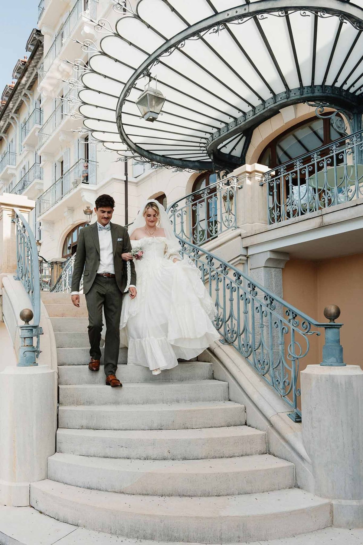 Couple descending curved staircase under ornate canopy at Palace de Menthon Annecy
