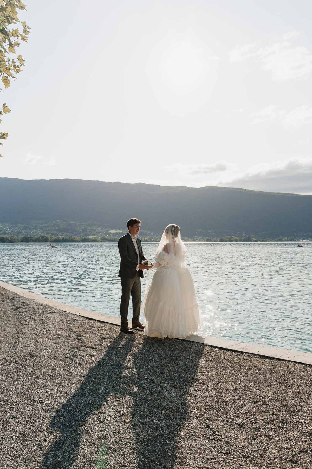 Couple at Lake Annecy water's edge at golden hour with mountain silhouettes at Palace de Menthon