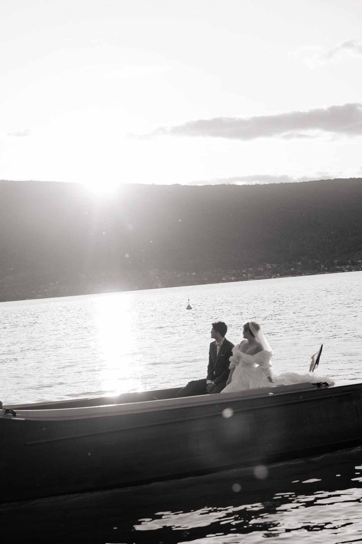 Couple silhouetted on boat at sunset on Lake Annecy in black and white at Palace de Menthon
