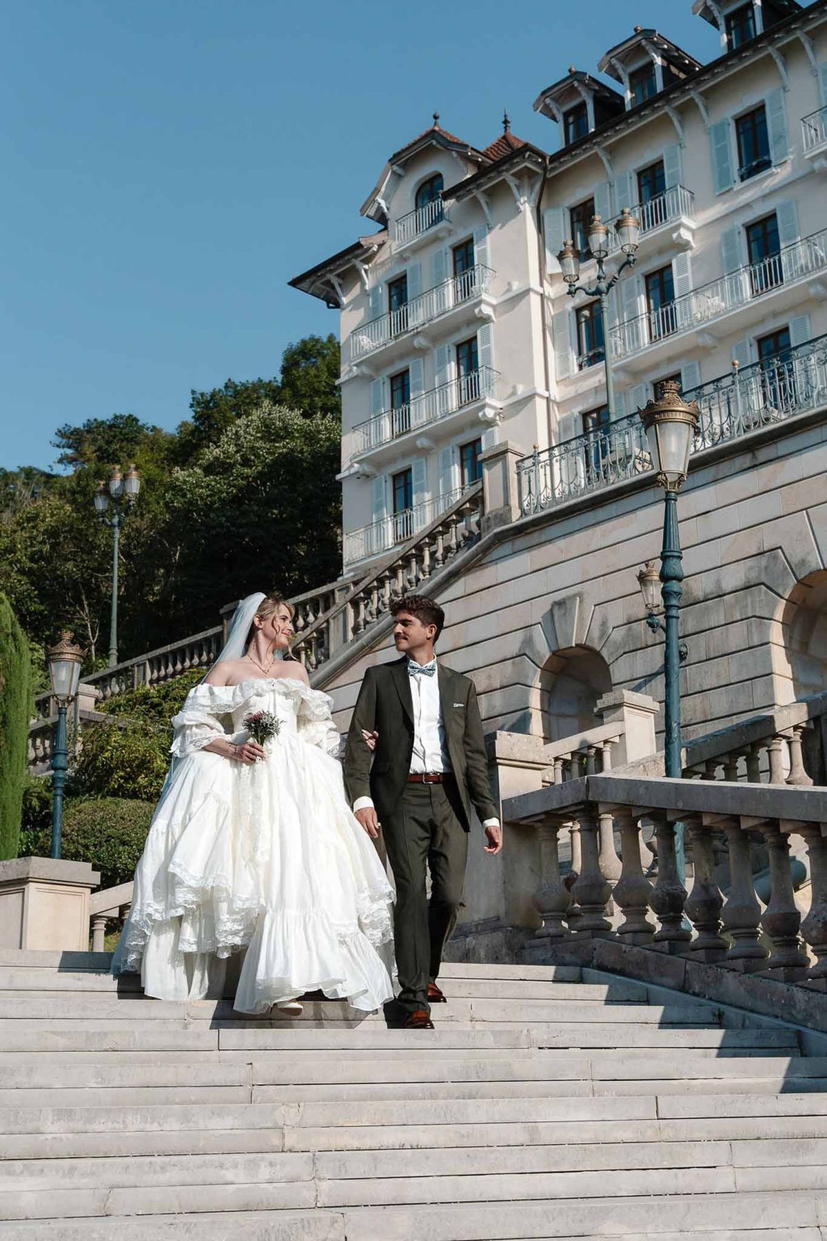 Couple walking down grand staircase with Palace de Menthon façade behind