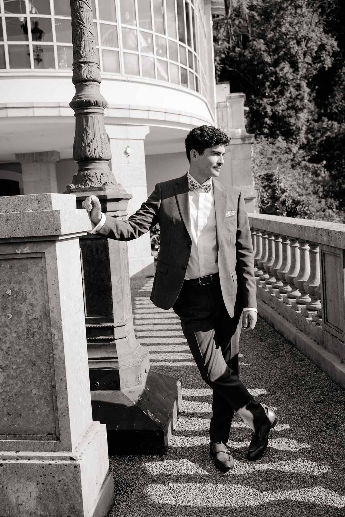 Groom leaning on stone balustrade in black and white at Palace de Menthon Annecy