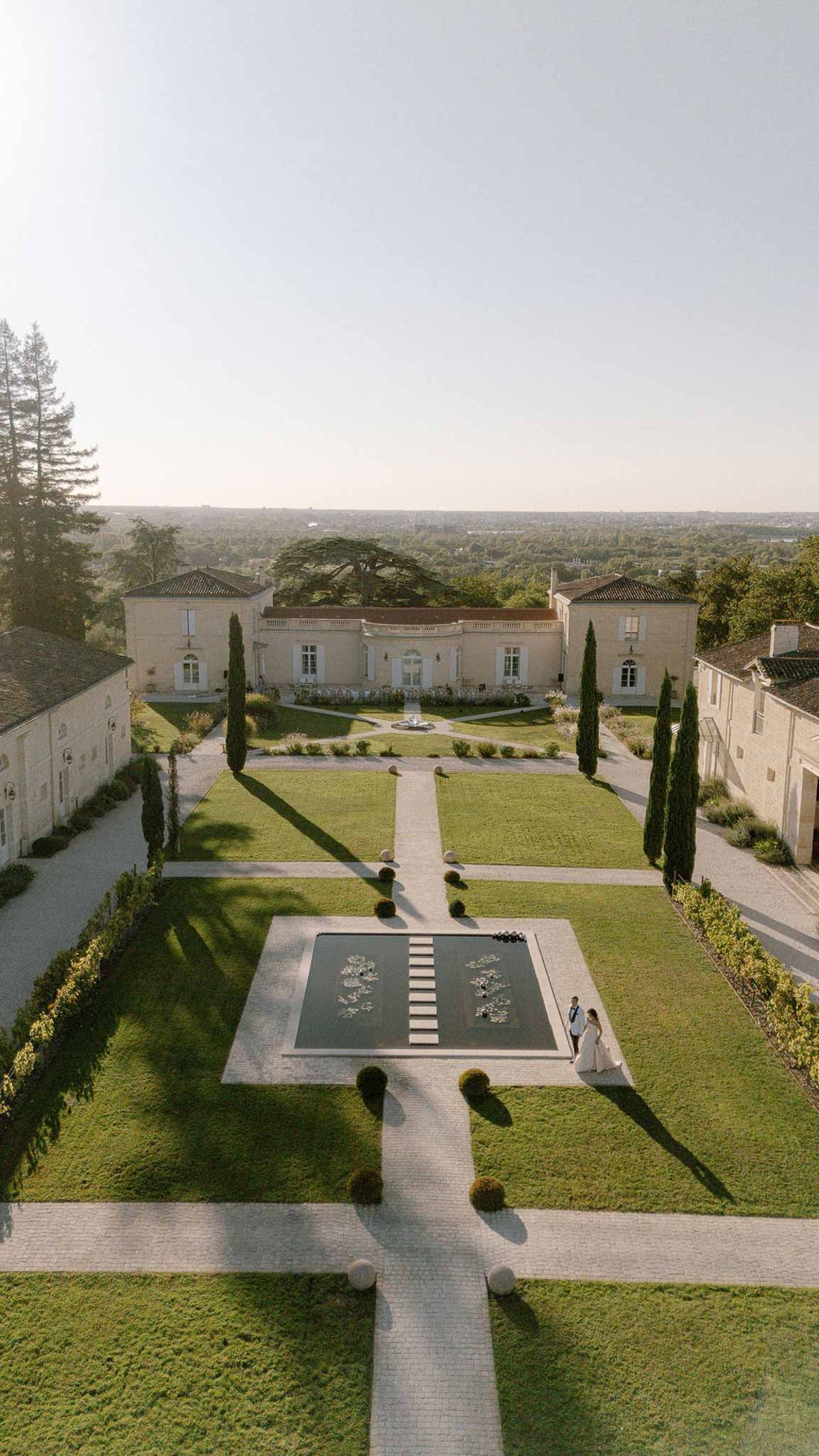 Aerial view of formal chateau garden with reflecting pool boxwood topiary cypress avenue and ceremony chairs