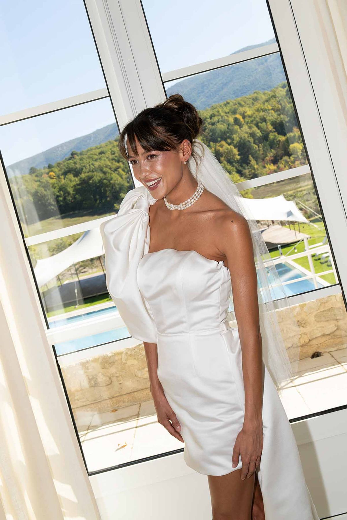 Bride in short dress with oversized ribbon getting ready