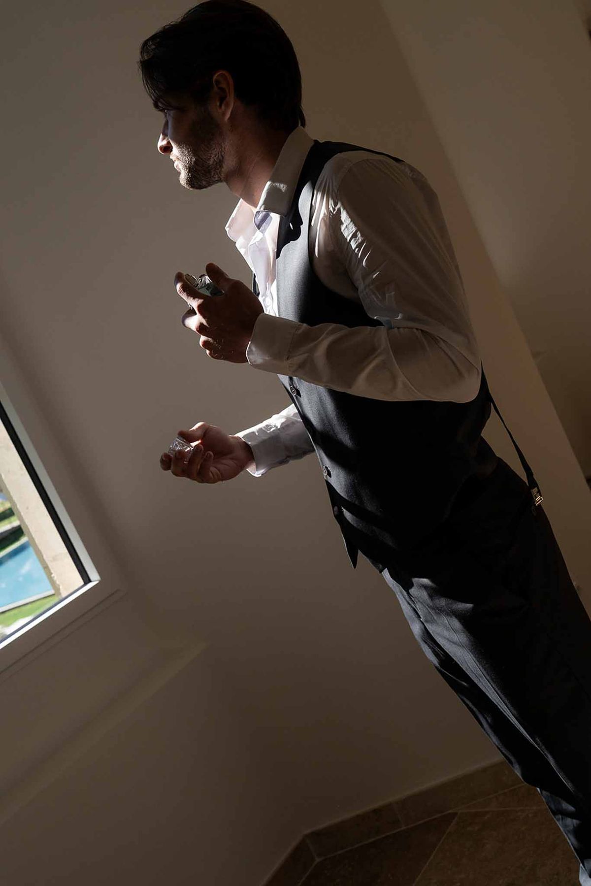Groom spraying perfume getting ready at Château du Griffon