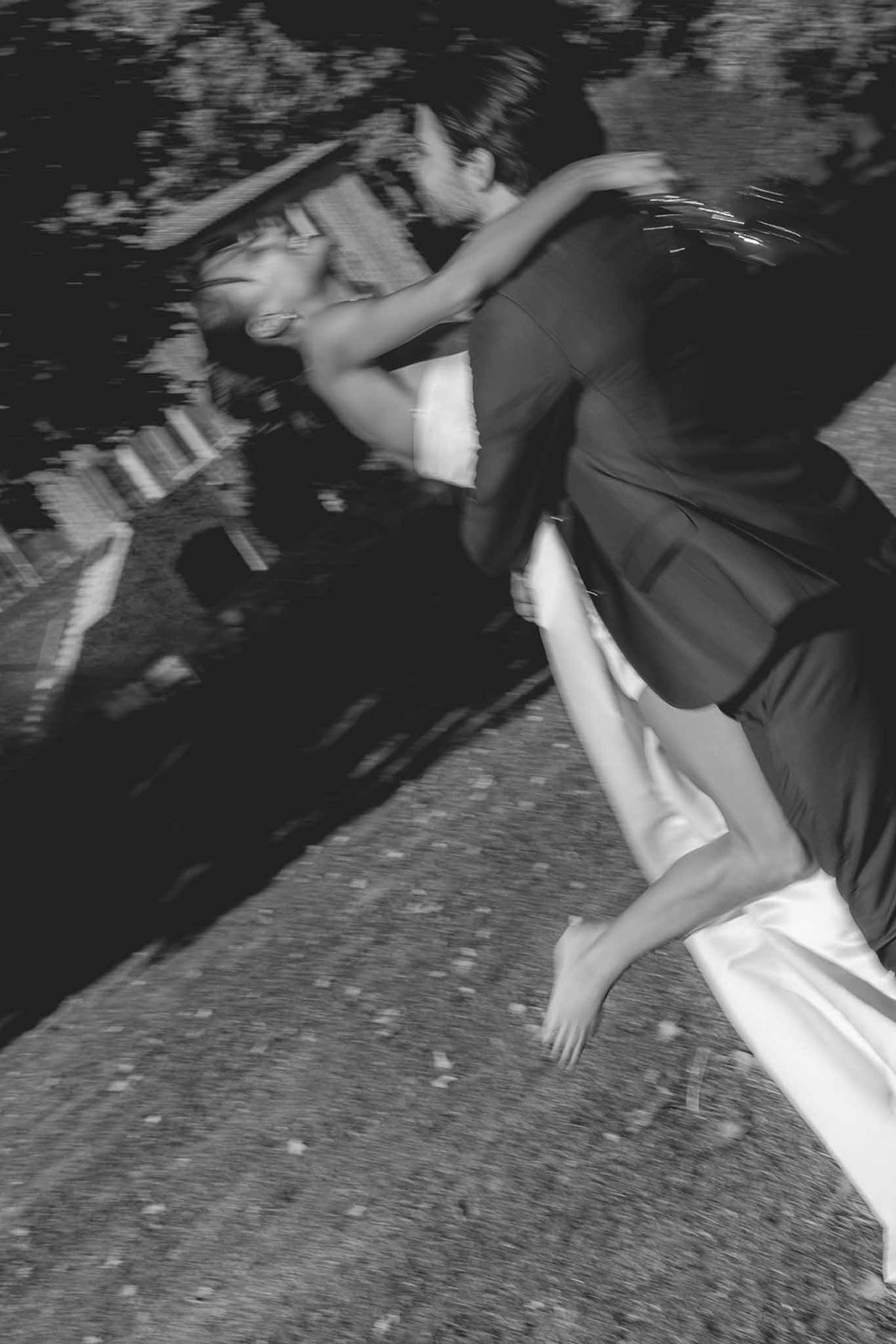 Groom carrying bride twirling in garden at Château du Griffon