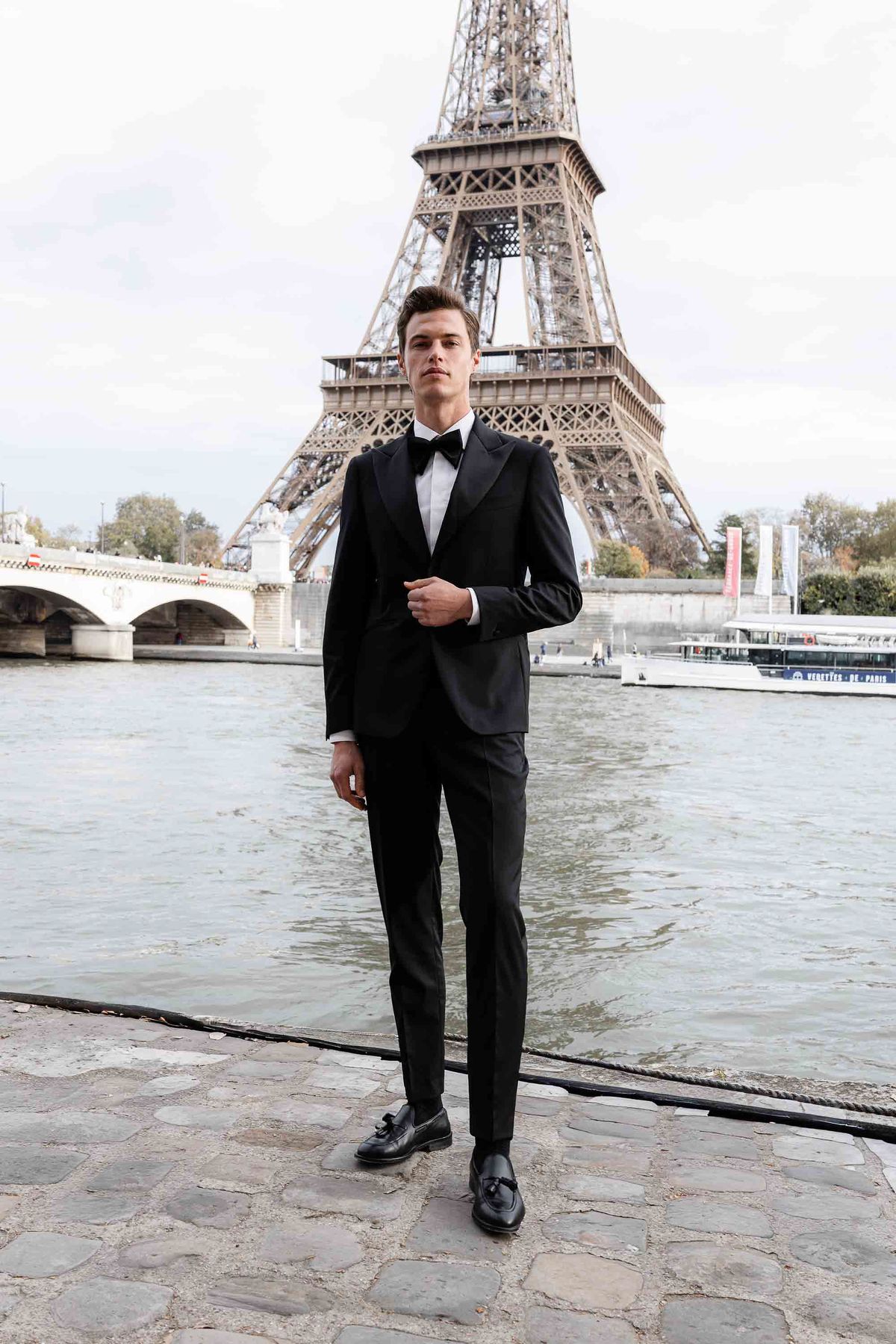 Groom in a black tuxedo by the river during a Parisian autumn wedding editorial