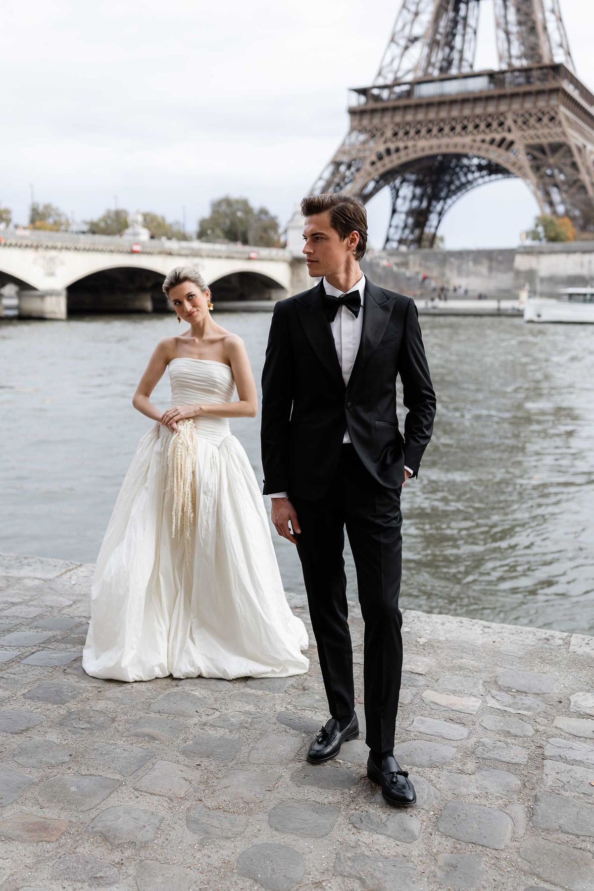 Bride and groom by a Seine bridge during a Parisian wedding editorial