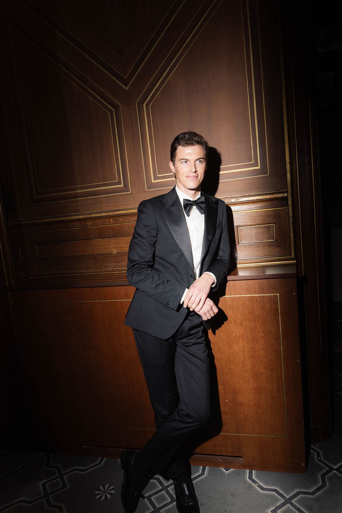 Groom in a black tuxedo in a candlelit Parisian salon