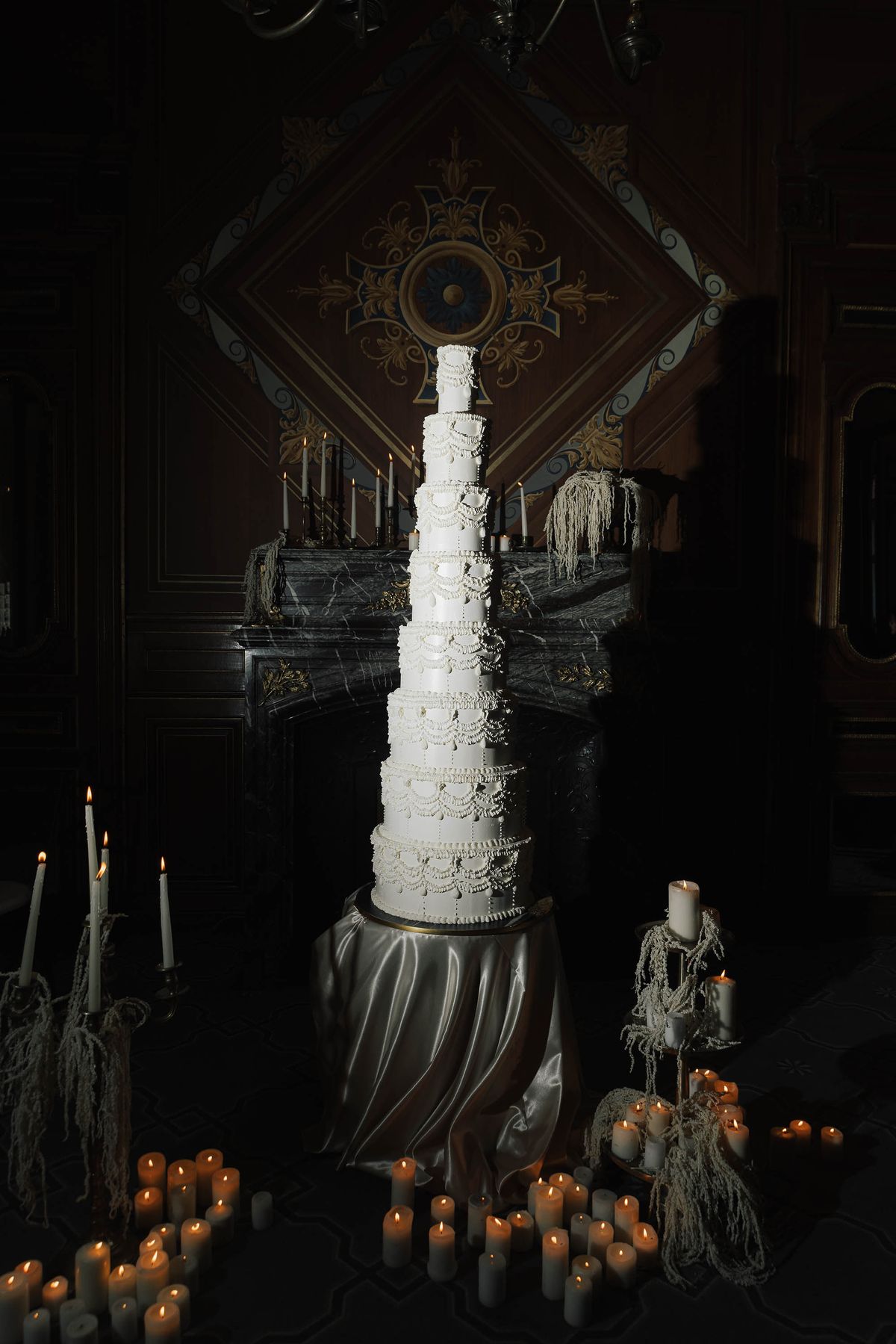 Towering wedding cake lit by candles in the reception at La Galerie Bourbon