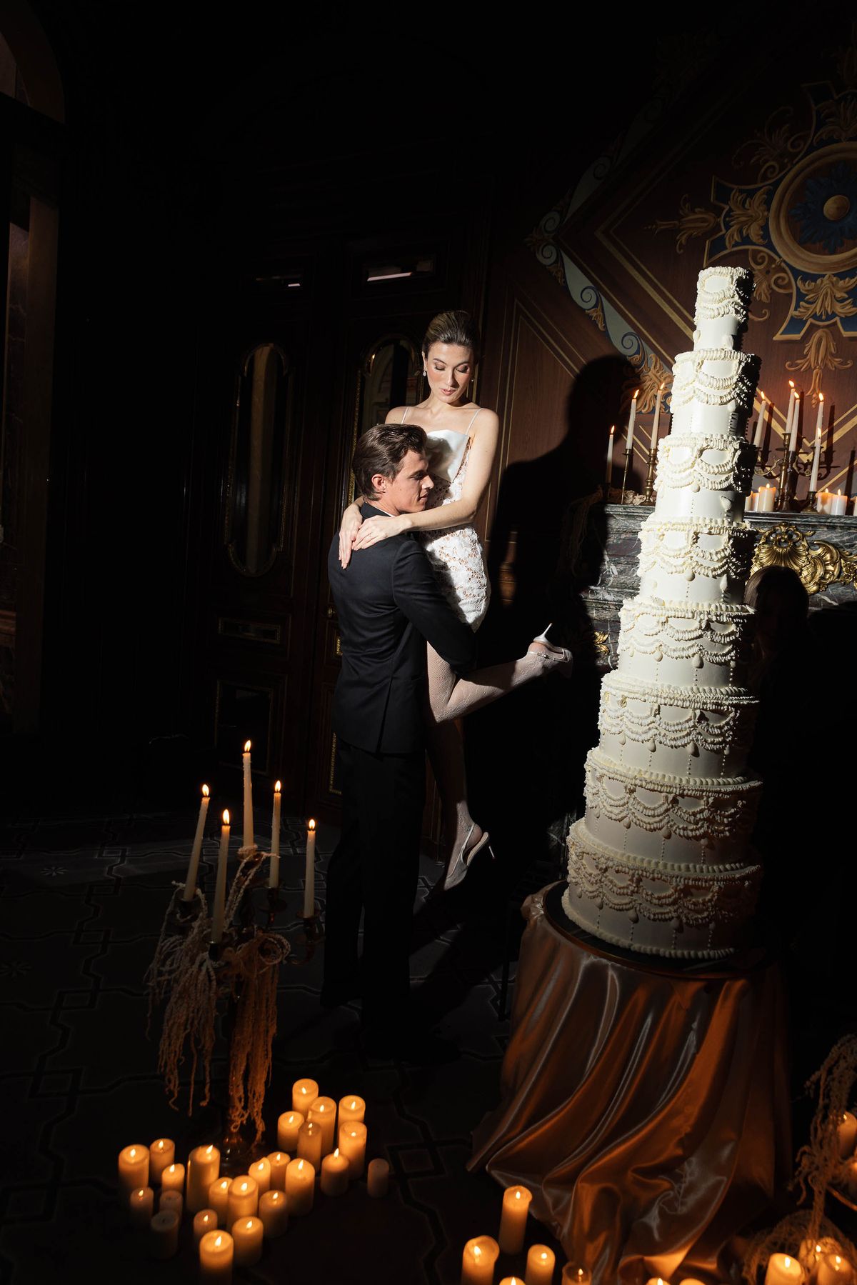 Couple embracing beside the wedding cake by candlelight