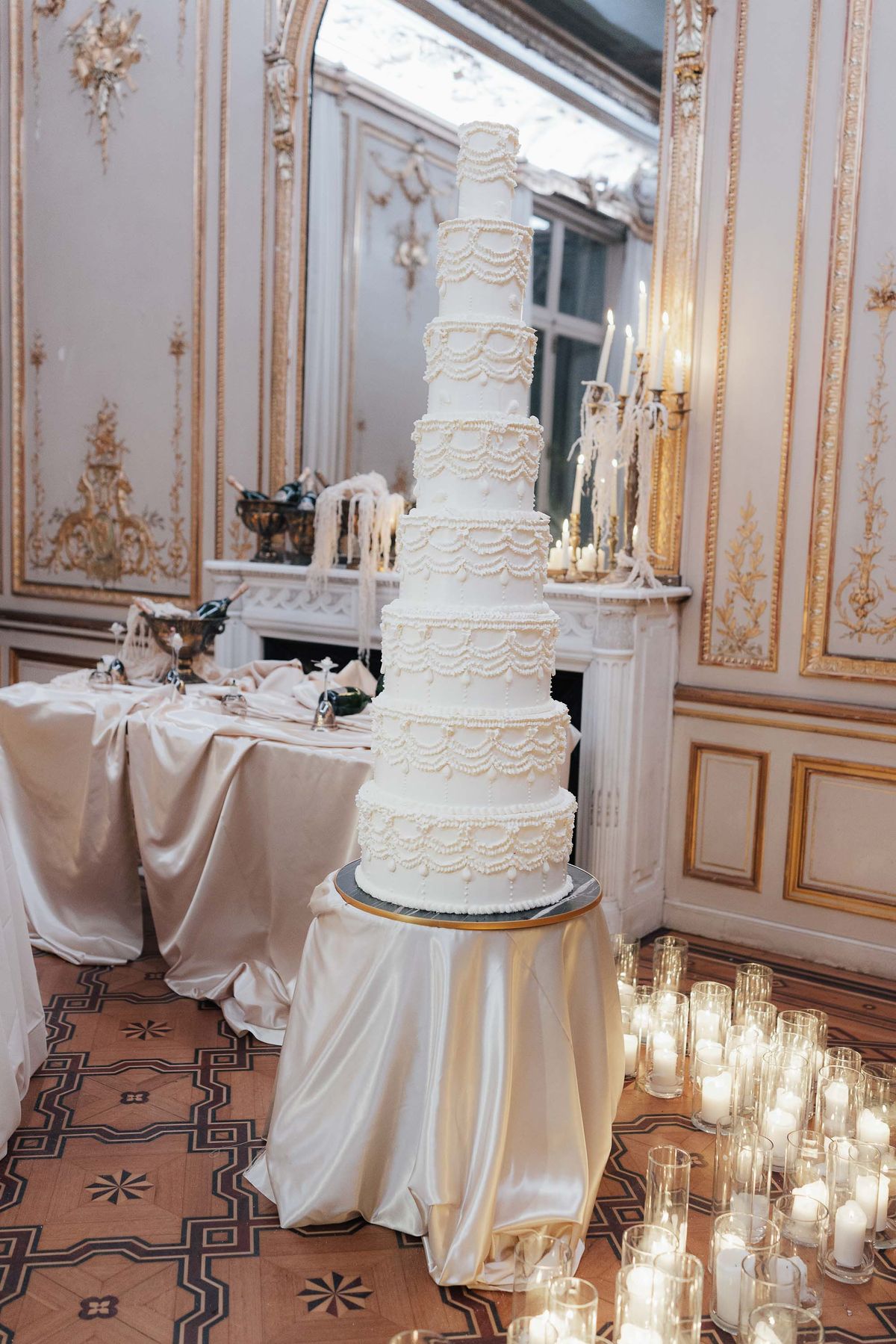 Tiered wedding cake beside the fireplace in the reception salon