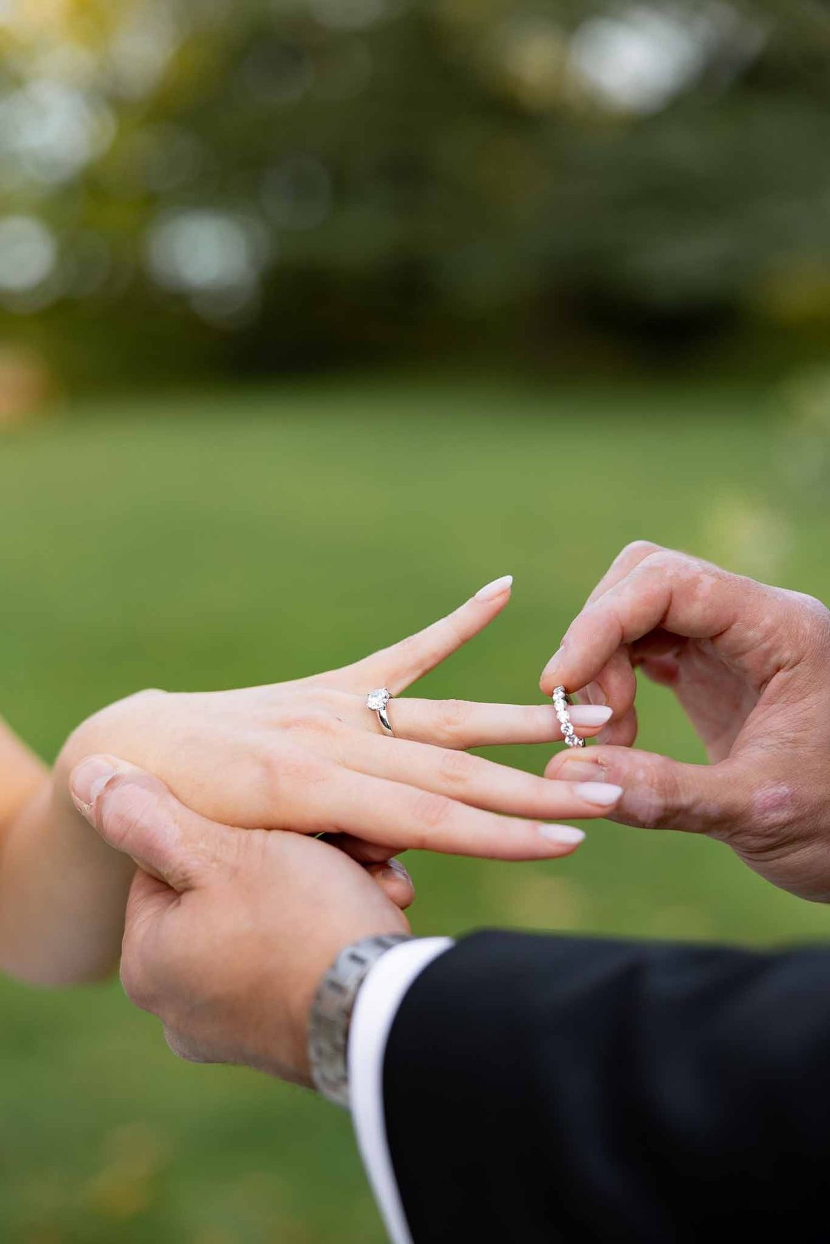 Groom placing diamond ring on bride's finger during ceremony at Château Comtesse Lafond