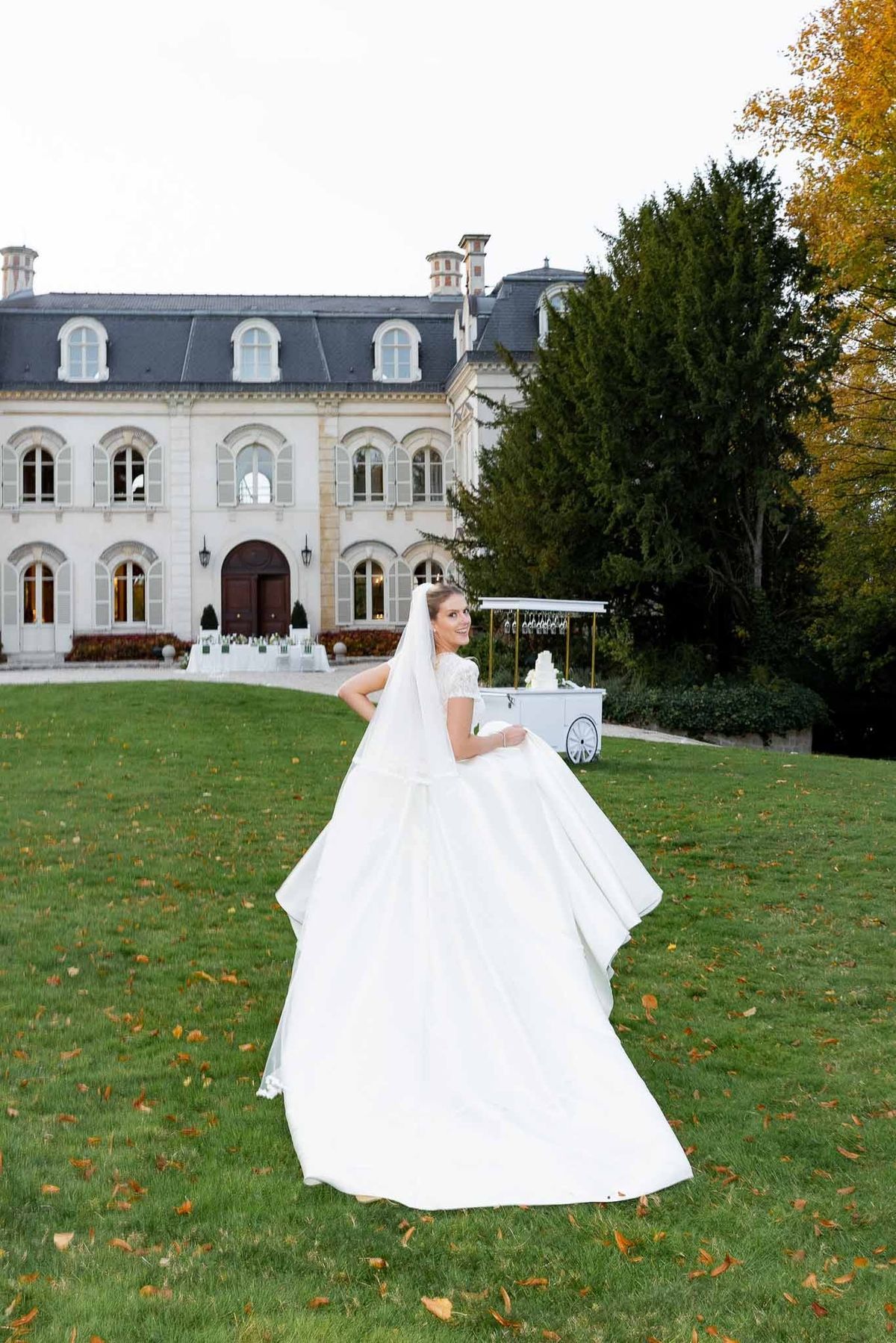 Bride twirling ball gown on autumn lawn before Château Comtesse Lafond