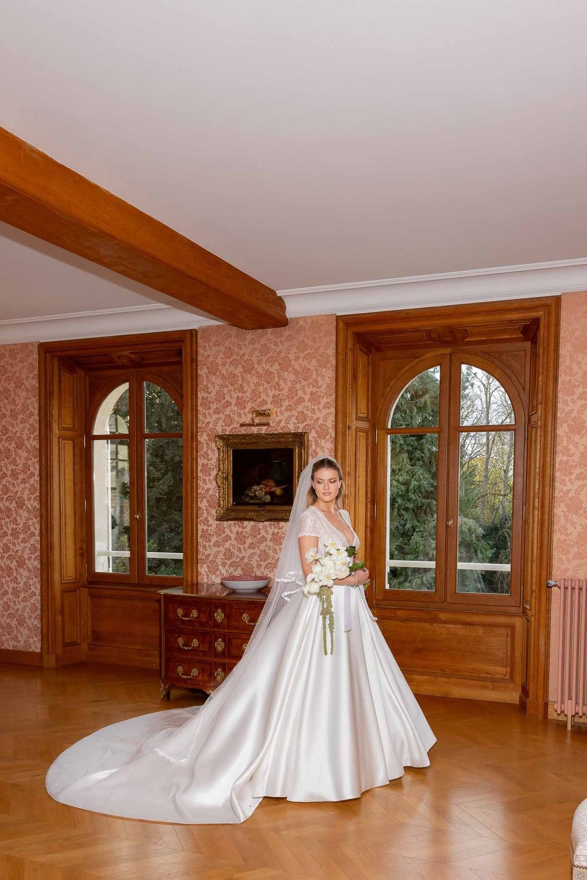 Bride with bouquet in rose-papered salon at Château Comtesse Lafond