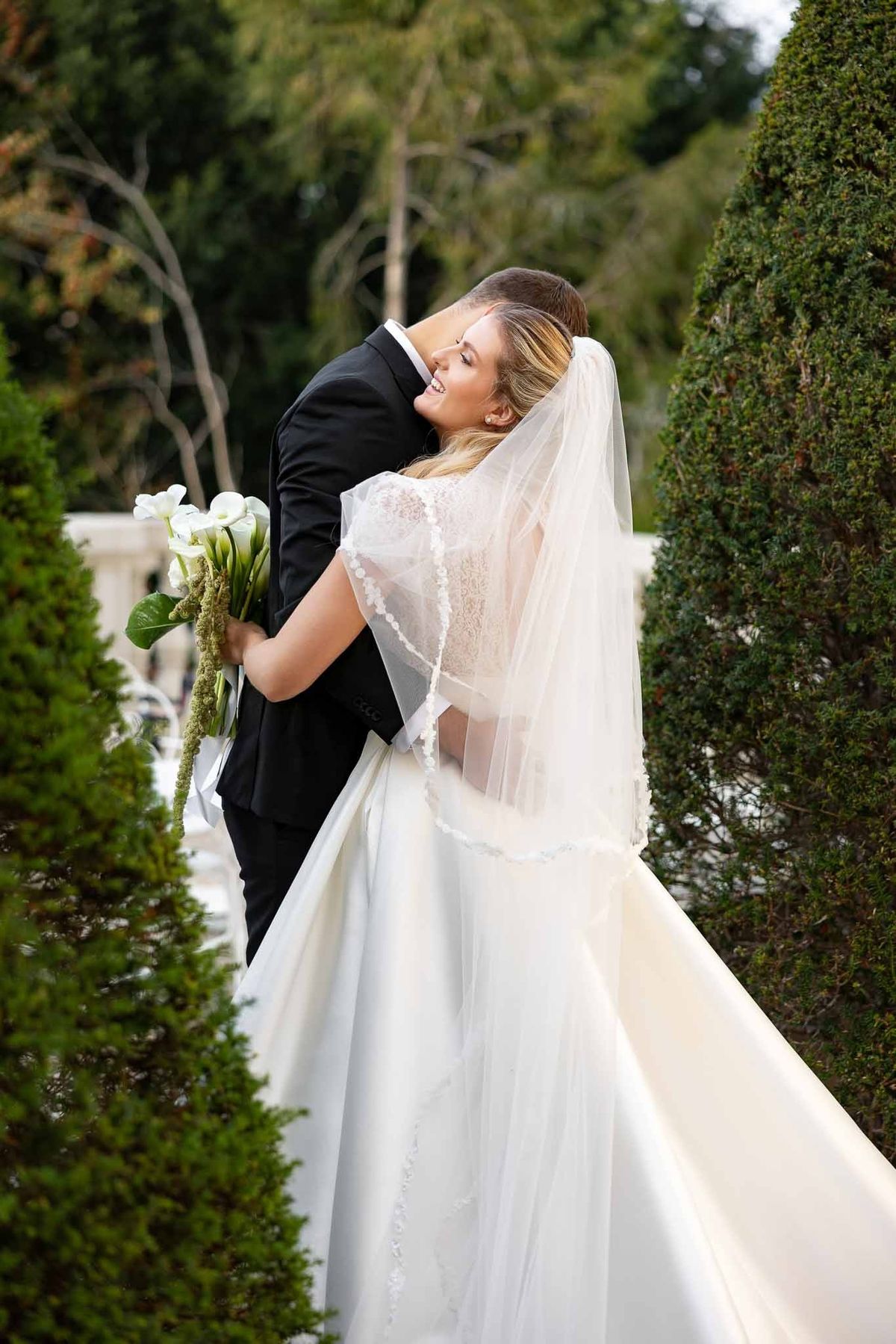 Groom dipping bride by topiary path with bouquet at Château Comtesse Lafond