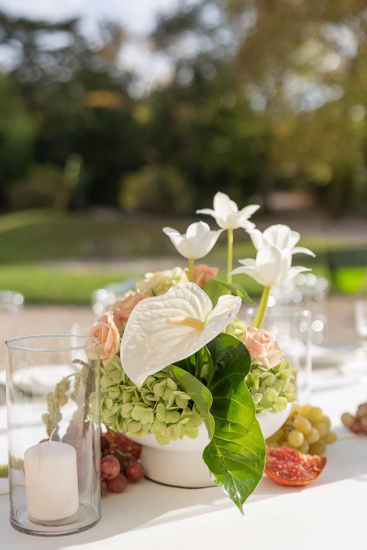 Anthurium and hydrangea centrepiece with hurricane candle in garden at Château Comtesse Lafond