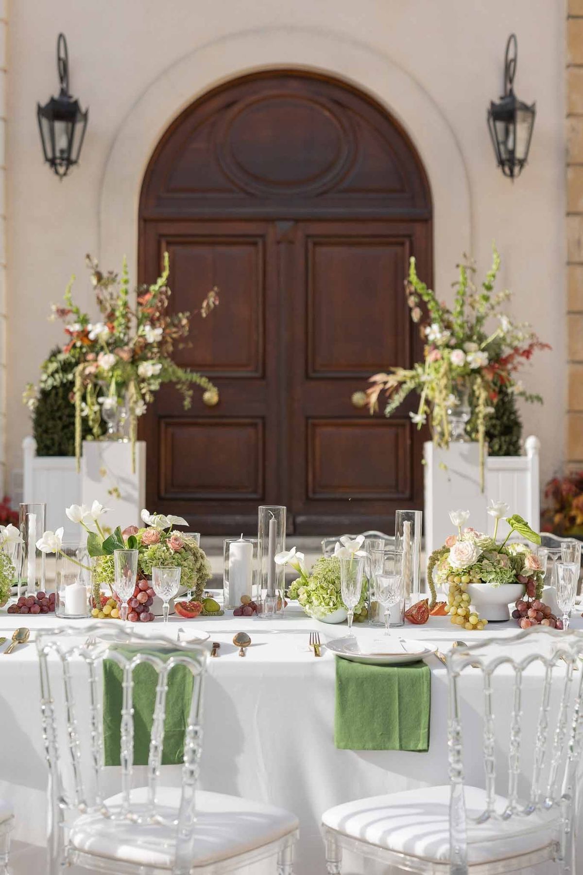 Outdoor reception tables with clear chairs and tall florals in courtyard at Château Comtesse Lafond