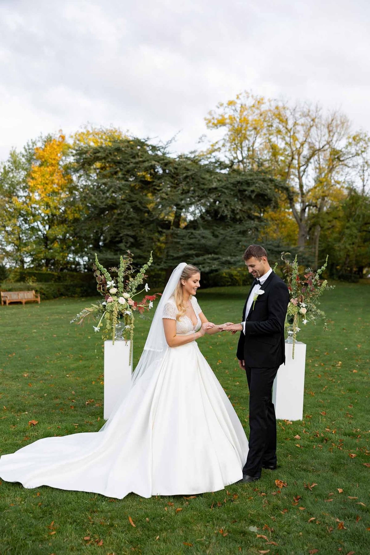 Couple exchanging rings at outdoor ceremony with floral plinths at Château Comtesse Lafond