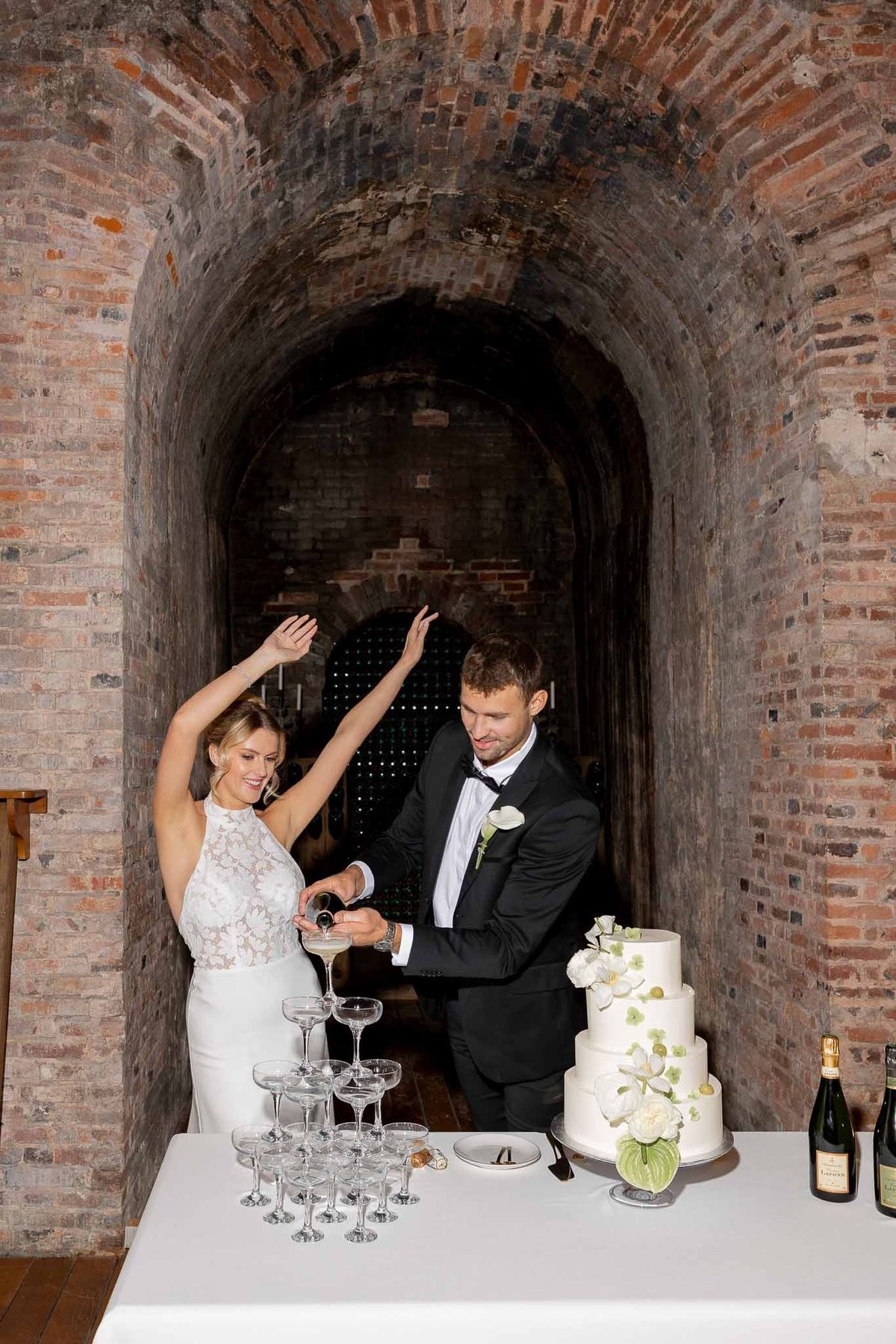 Couple pouring champagne tower in wine cellar at Château Comtesse Lafond