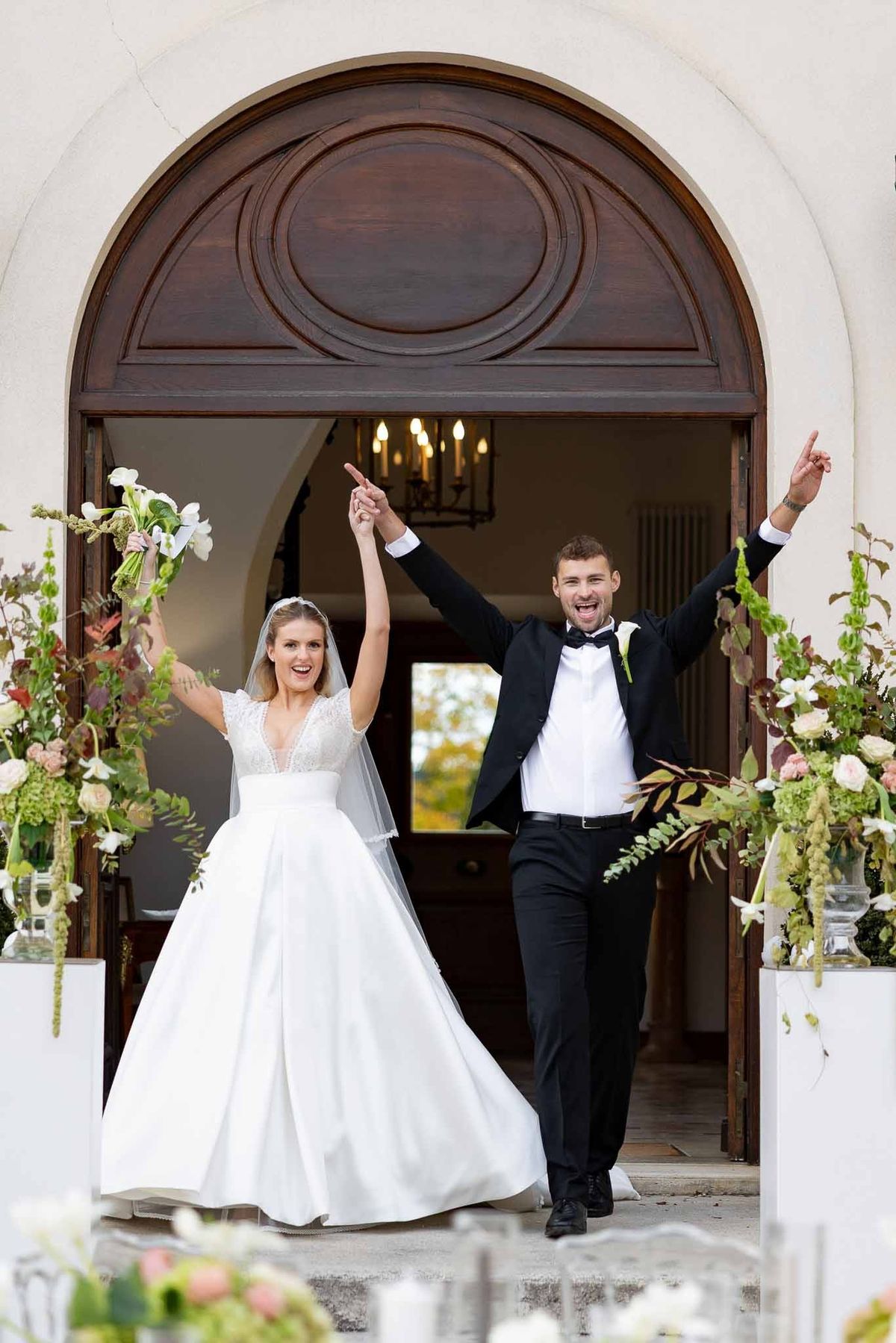 Couple celebrating entrance through arched doorway at Château Comtesse Lafond reception