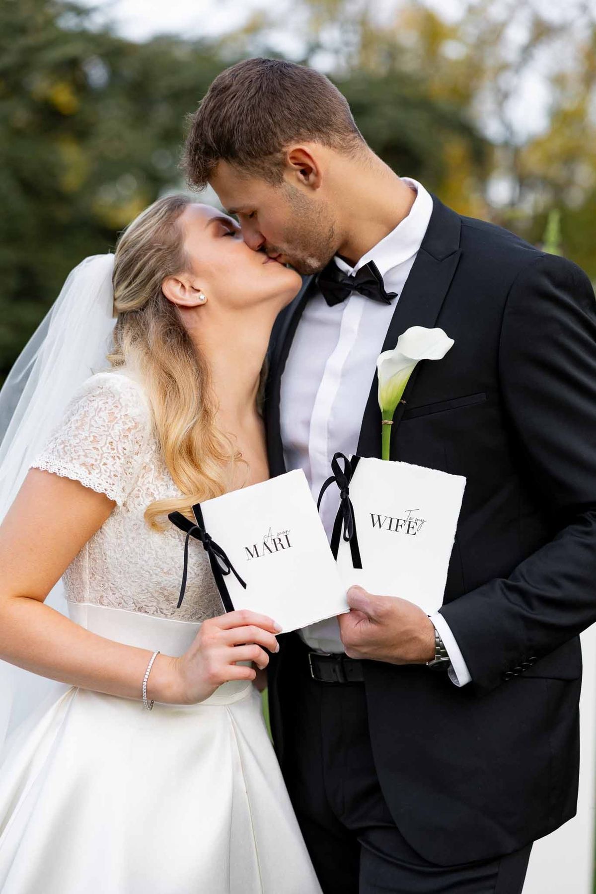 Couple kissing holding personalised vow booklets at Château Comtesse Lafond