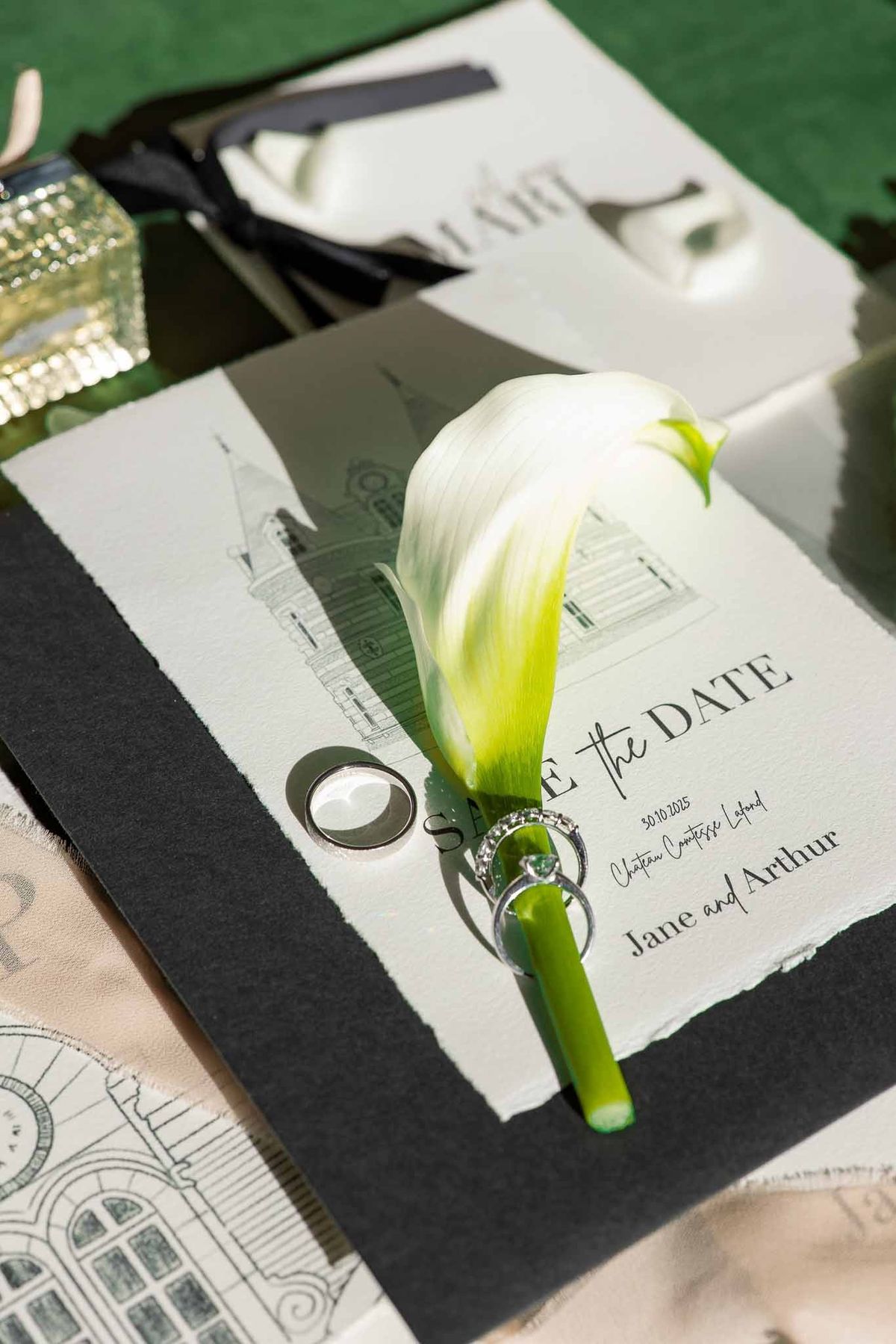 Stationery flat lay with château illustration, calla lily and rings at Château Comtesse Lafond