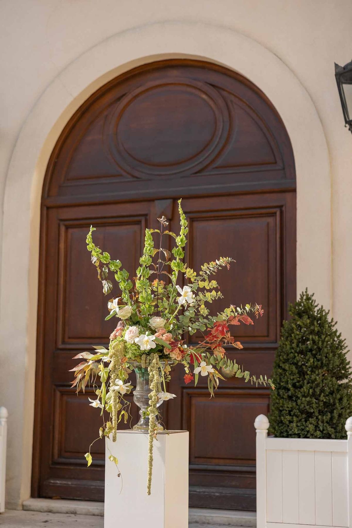 Tall autumn floral arrangement beside arched doorway at Château Comtesse Lafond