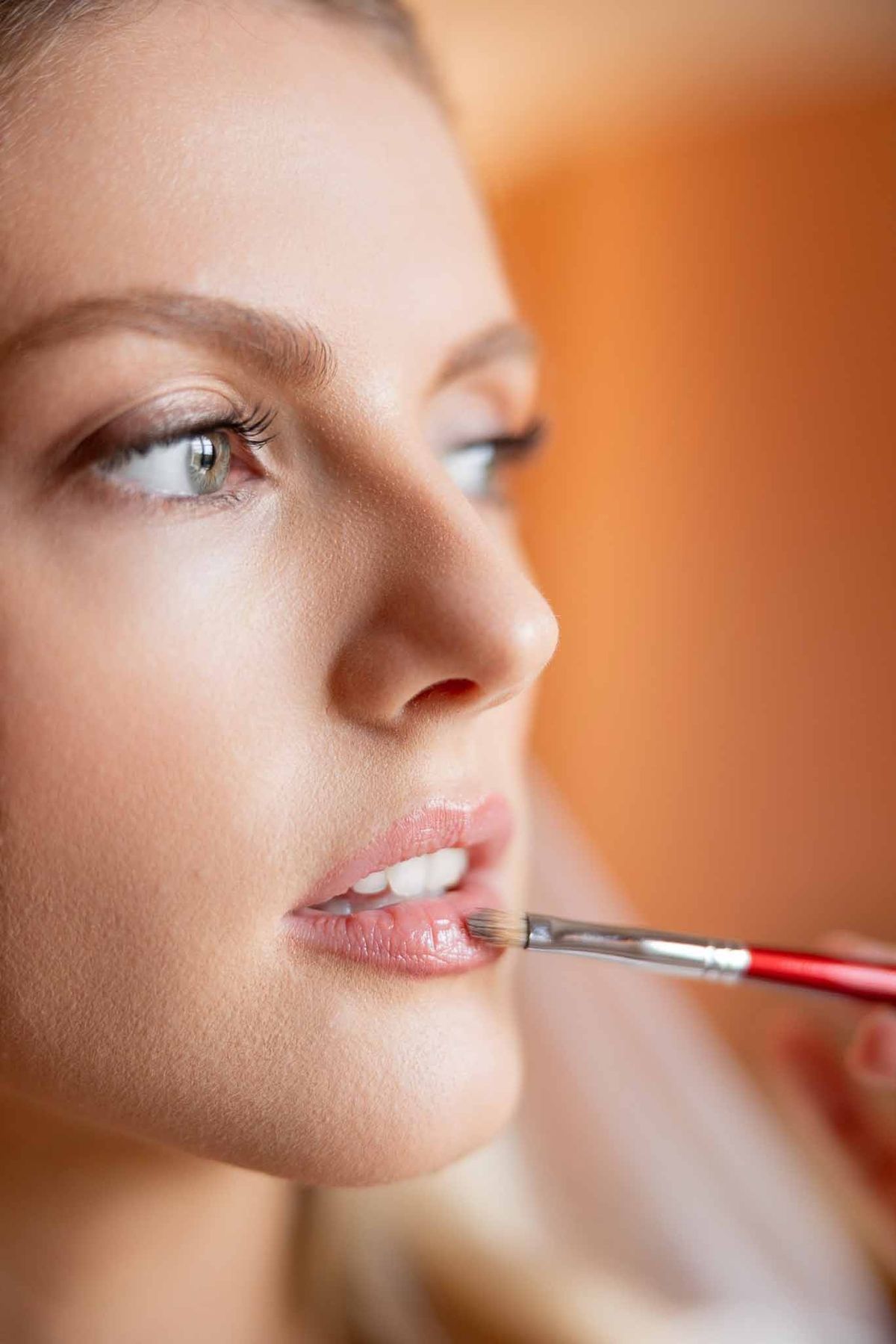 Makeup artist applying lipstick to bride close-up at Château Comtesse Lafond