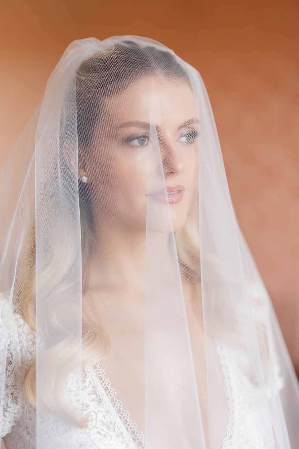 Bride looking through veil with pearl earrings at Château Comtesse Lafond