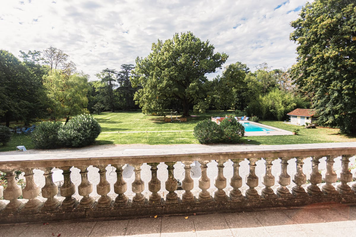 Elevated terrace view over chateau grounds with swimming pool lawn ceremony area and mature trees