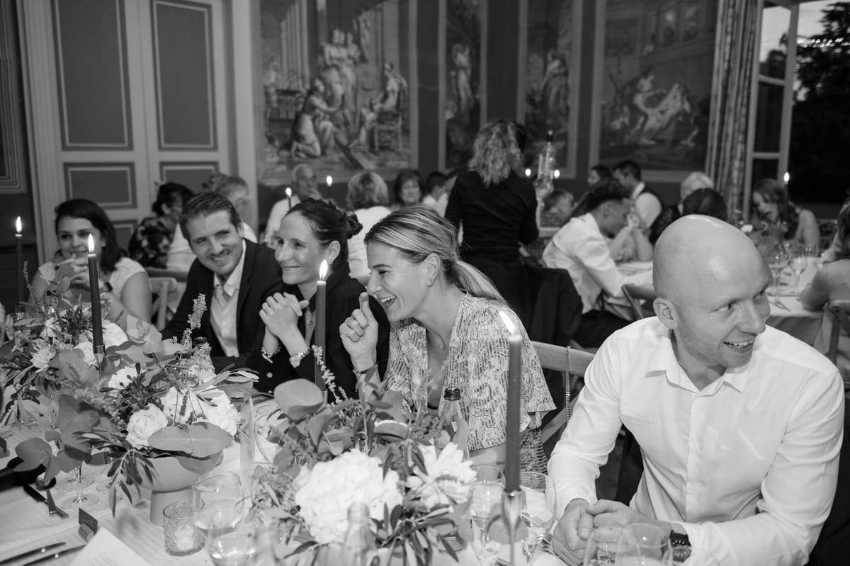 Black and white candlelit reception in painted ballroom with peony centrepieces and 20 laughing guests