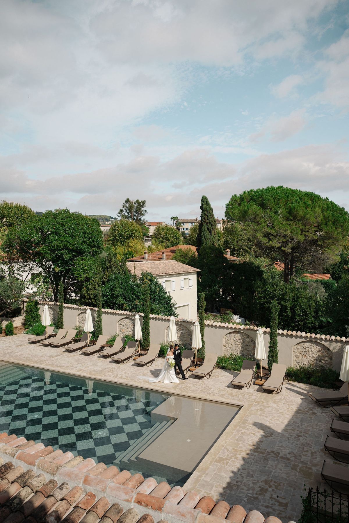Aerial view of couple beside checkerboard pool at Provence wedding venue