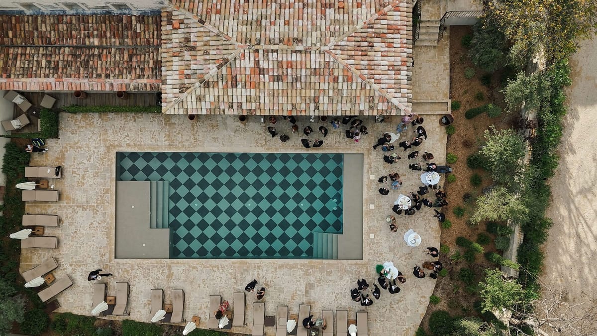 Aerial view of checkerboard pool and cocktail hour gathering at venue