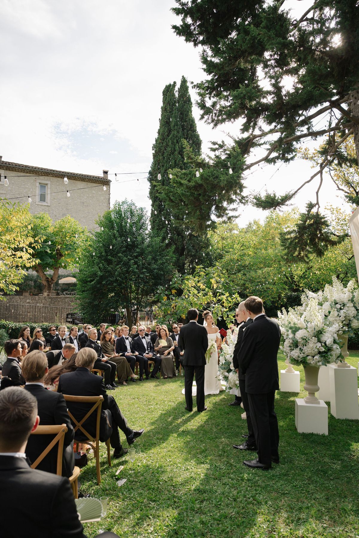Outdoor garden ceremony at chateau with white florals and seated guests