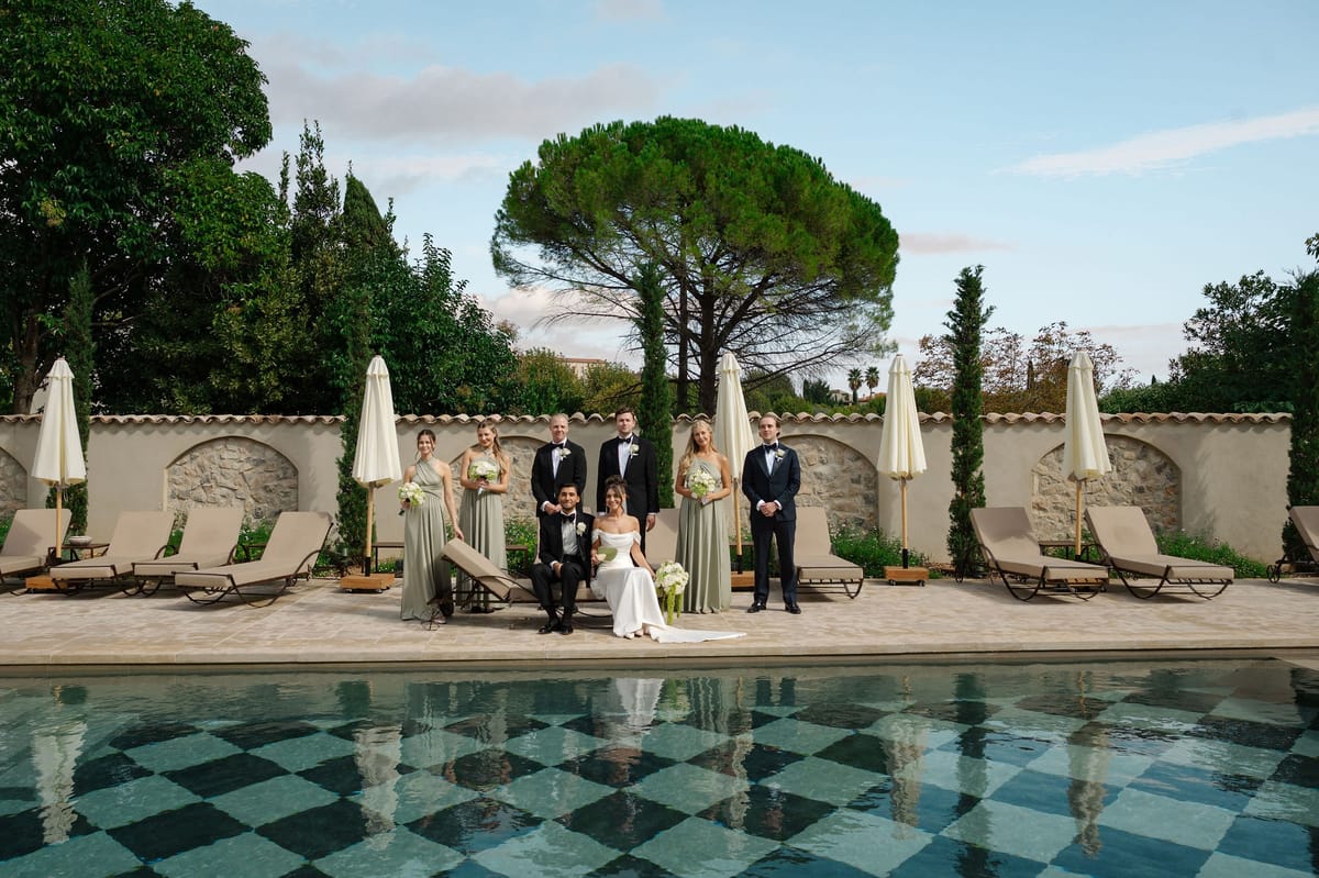 Formal bridal party portrait beside checkerboard pool at French venue