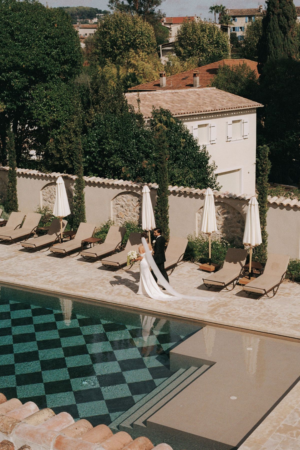 Aerial perspective of couple walking poolside at French chateau venue