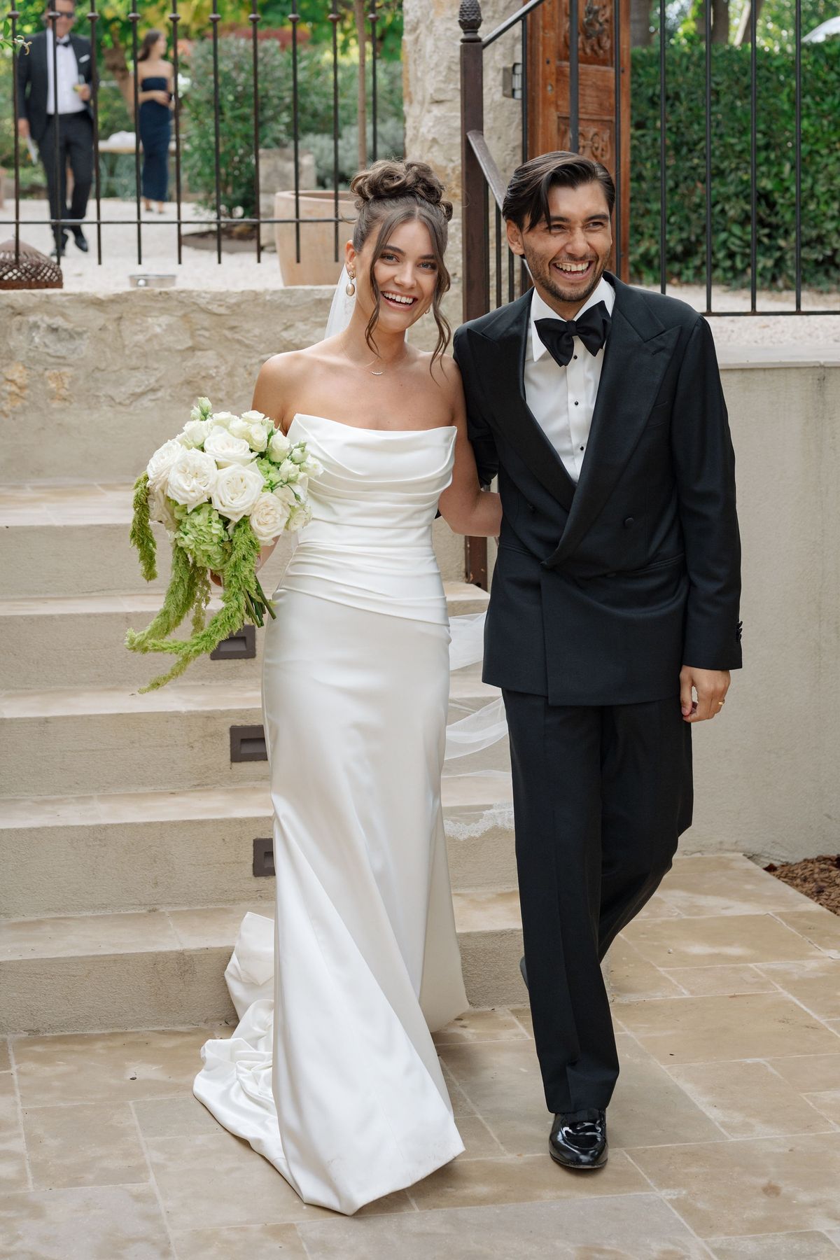 Smiling bride and groom walking down stone steps after the ceremony
