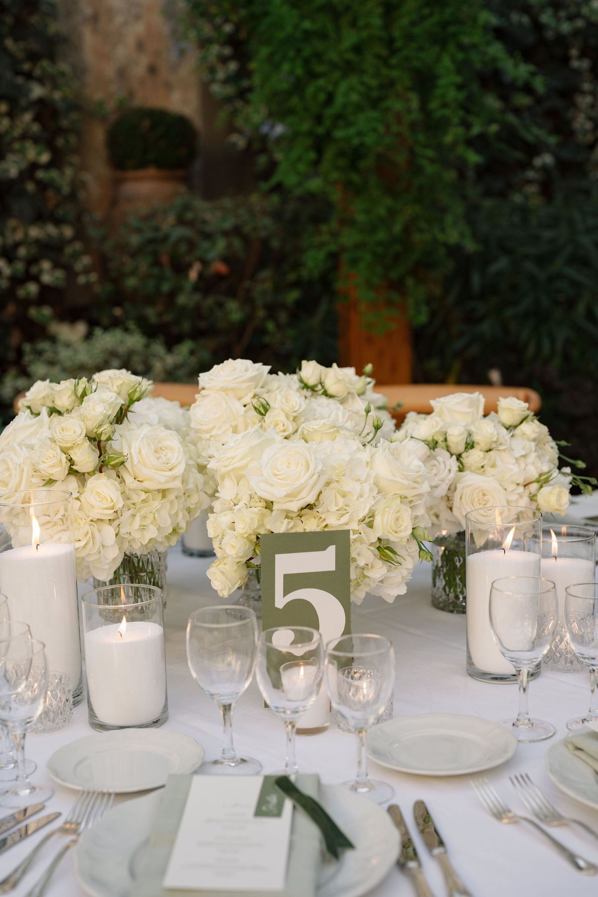 Reception centerpiece with white roses, candles, and sage table number