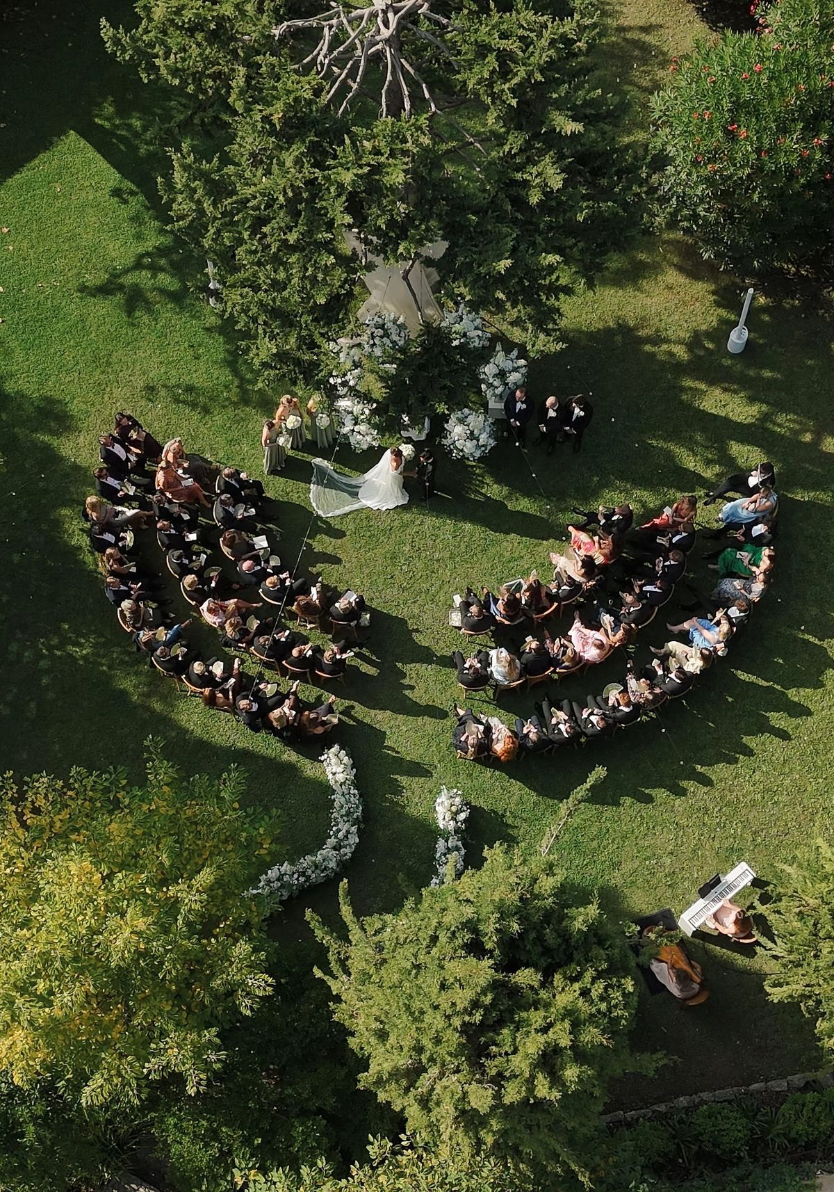 Drone view of curved ceremony seating around floral altar in garden