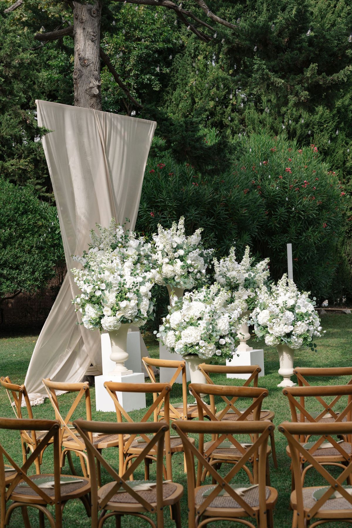 Ceremony aisle view of draped fabric arch and white floral arrangements