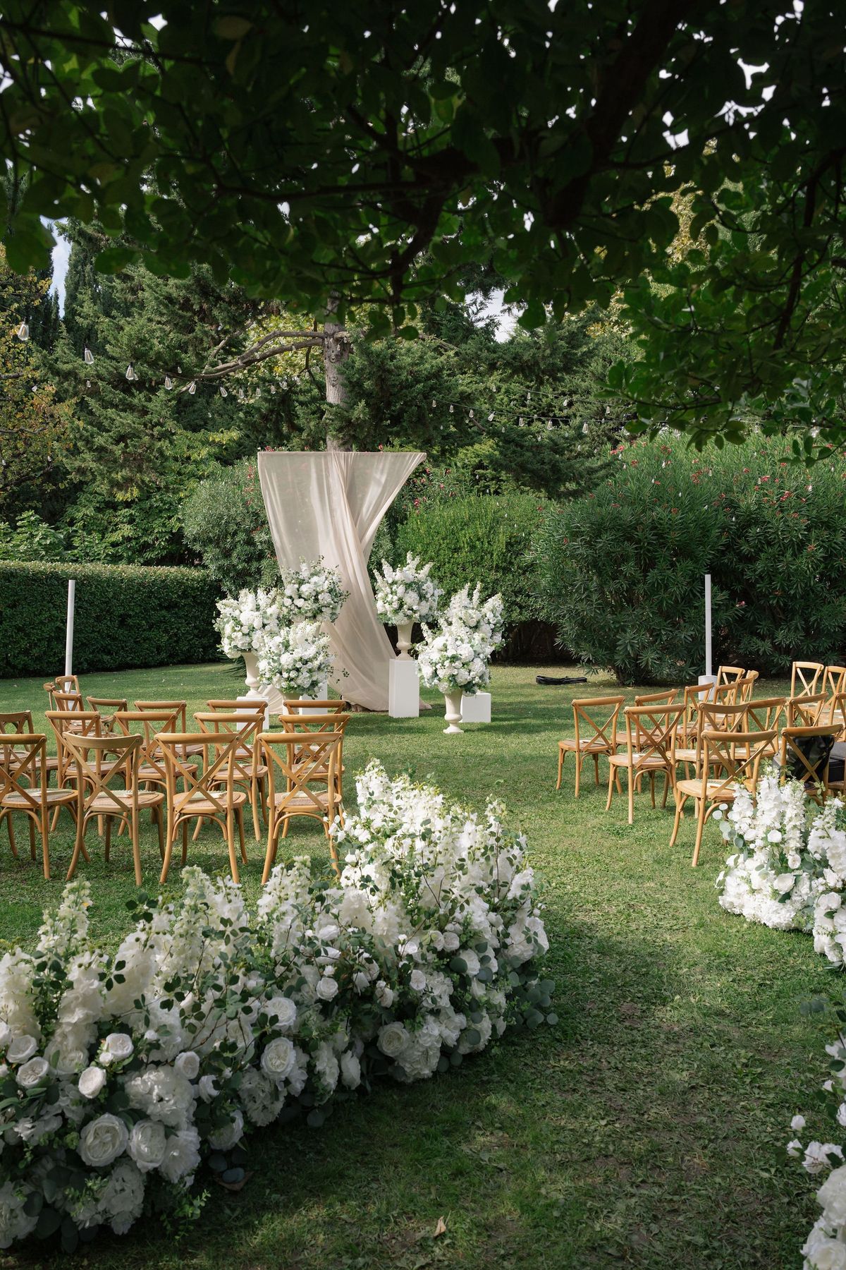 Garden ceremony layout with floral meadow aisle under tree canopy