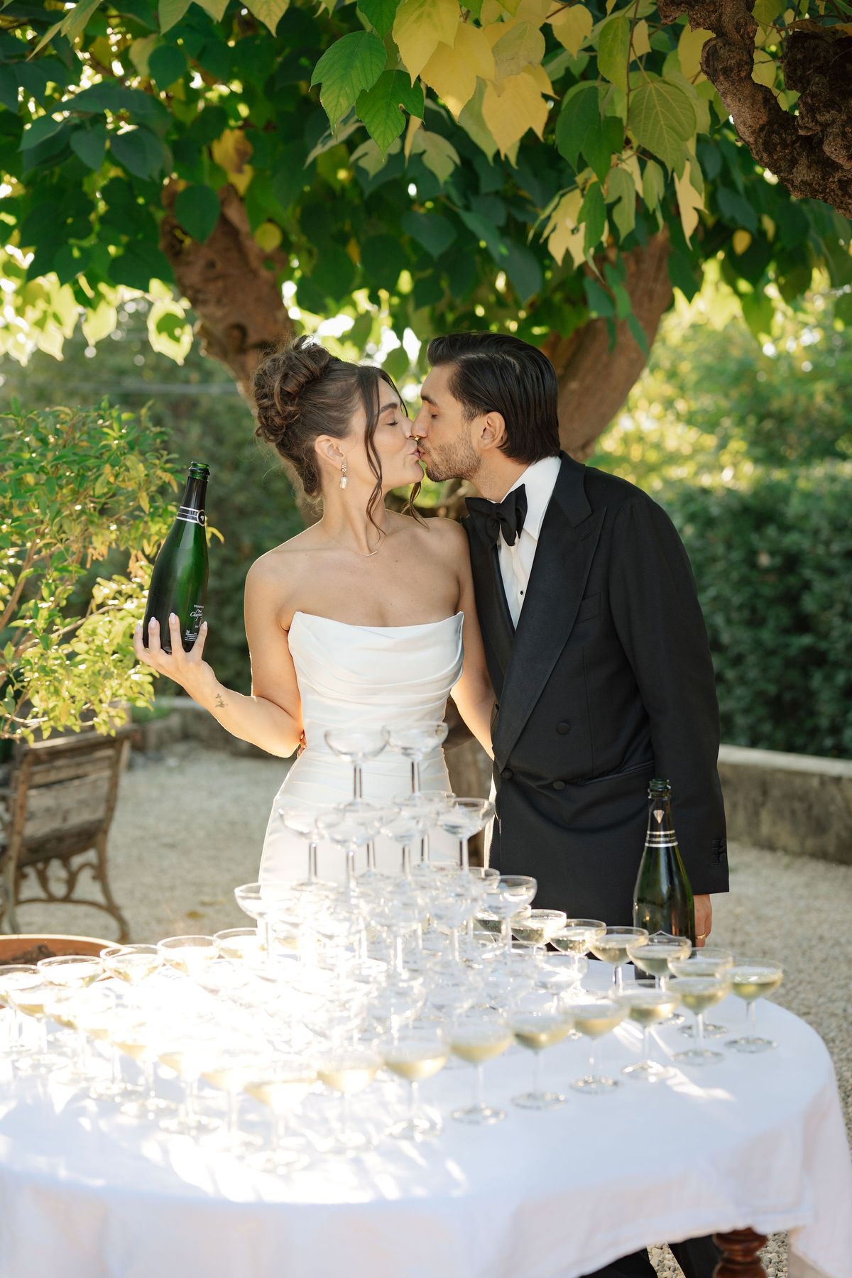Couple kissing behind champagne coupe tower at outdoor reception