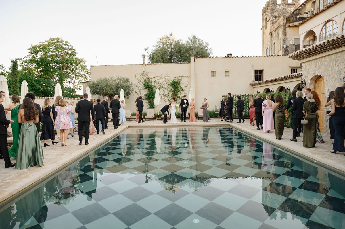 Cocktail hour gathering around checkerboard pool at French chateau