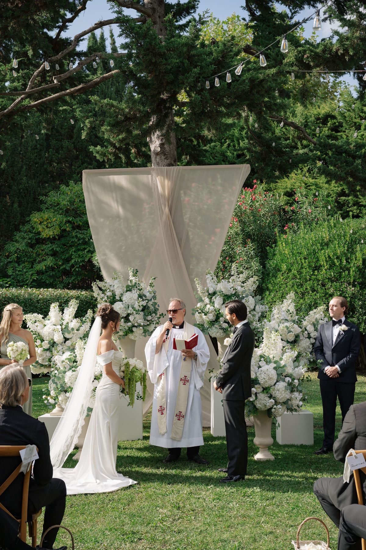 Officiant reading vows between bride and groom at outdoor altar