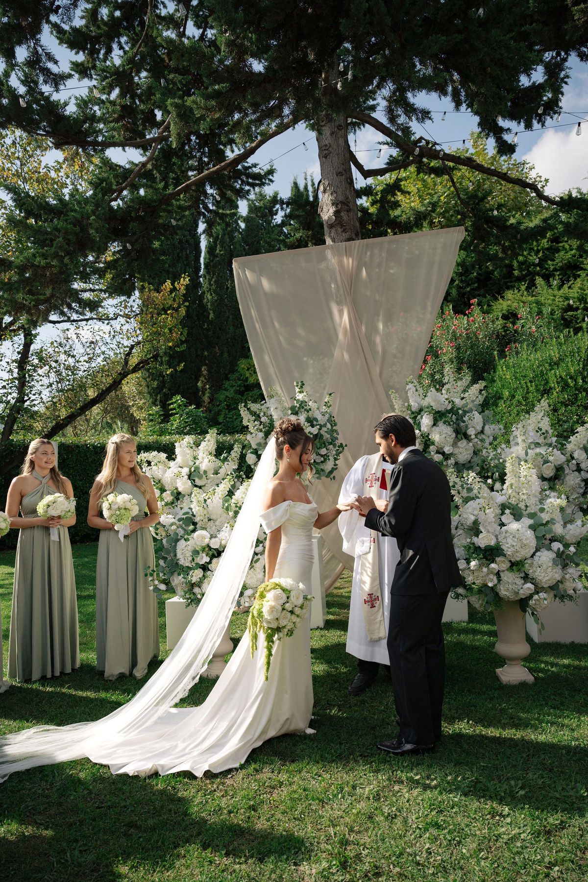 Couple exchanging rings at outdoor altar with white florals