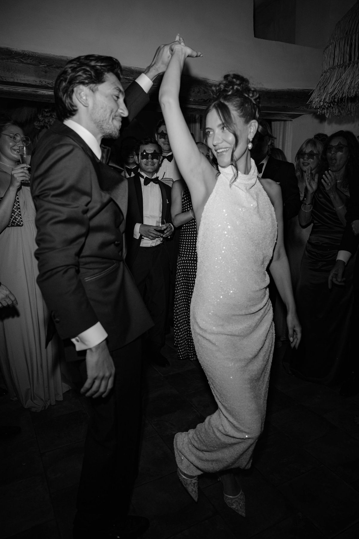 Bride in sequinned gown dancing with groom at indoor reception